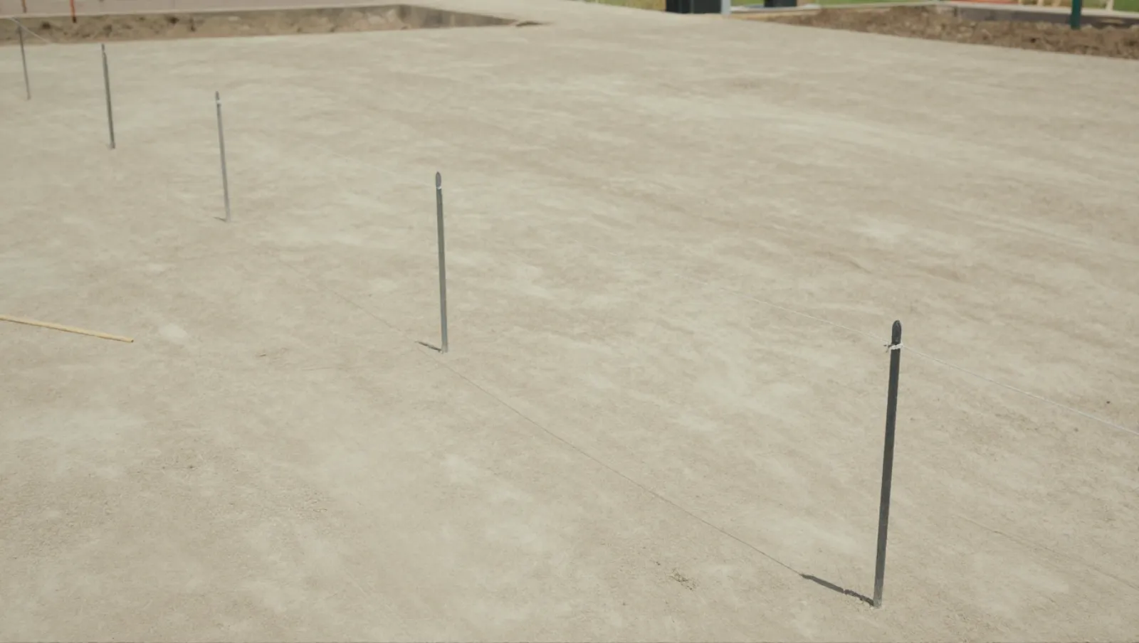 Stake-and-wire system marks boundary lines on flat concrete for construction alignment — Daniel Dean Land Clearing, Southeast Texas