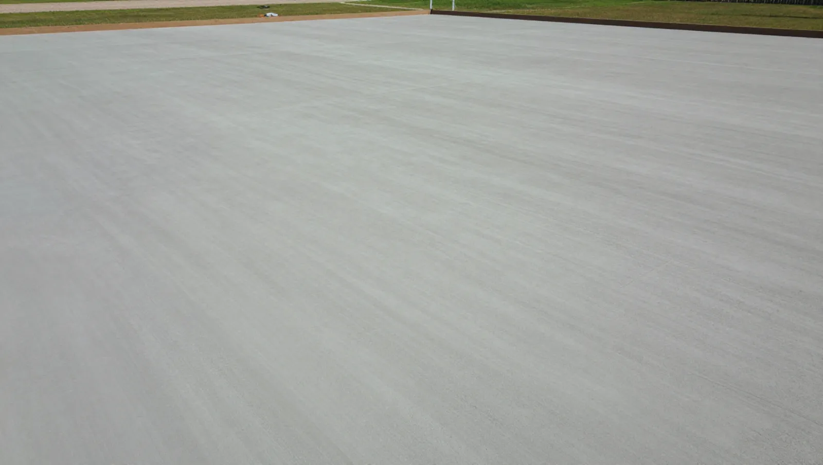 Smooth concrete terrain borders grassy areas; no machinery visible, work completed on the surface — Daniel Dean Land Clearing, Southeast Texas