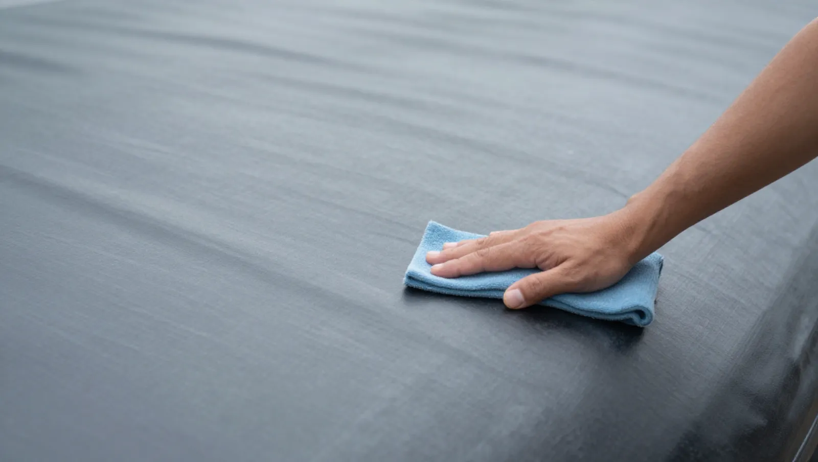 How Do I Patch EPDM Pond Liner Using Patch DIY Materials Hand uses blue cloth to clean dark smooth surface; no machinery, terrain is flat — Daniel Dean Land Clearing, Southeast Texas
