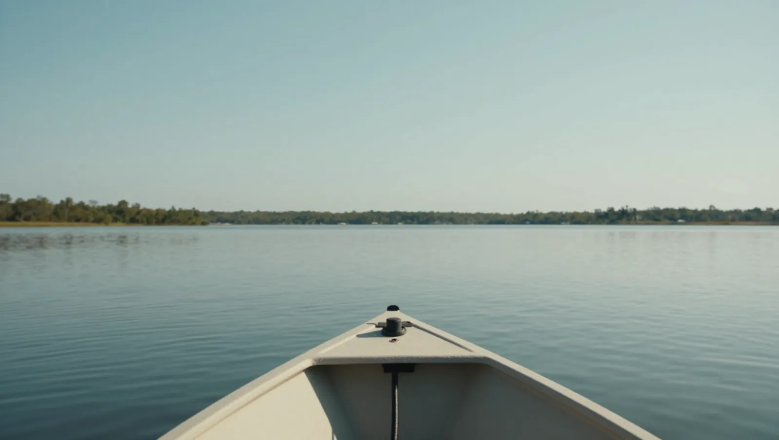 A boat navigates calm waters toward a distant tree-lined shore under clear skies — Daniel Dean Land Clearing, Southeast Texas