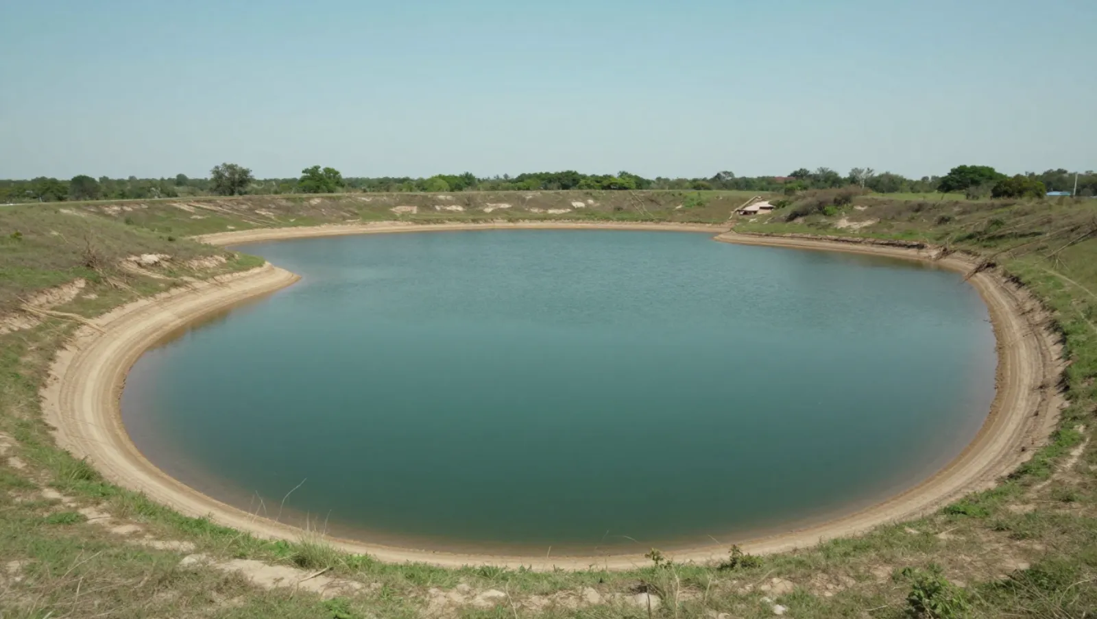 Reservoir with earthen embankment on grassy terrain; no machinery visible, earthwork construction ongoing — Daniel Dean Land Clearing, Southeast Texas