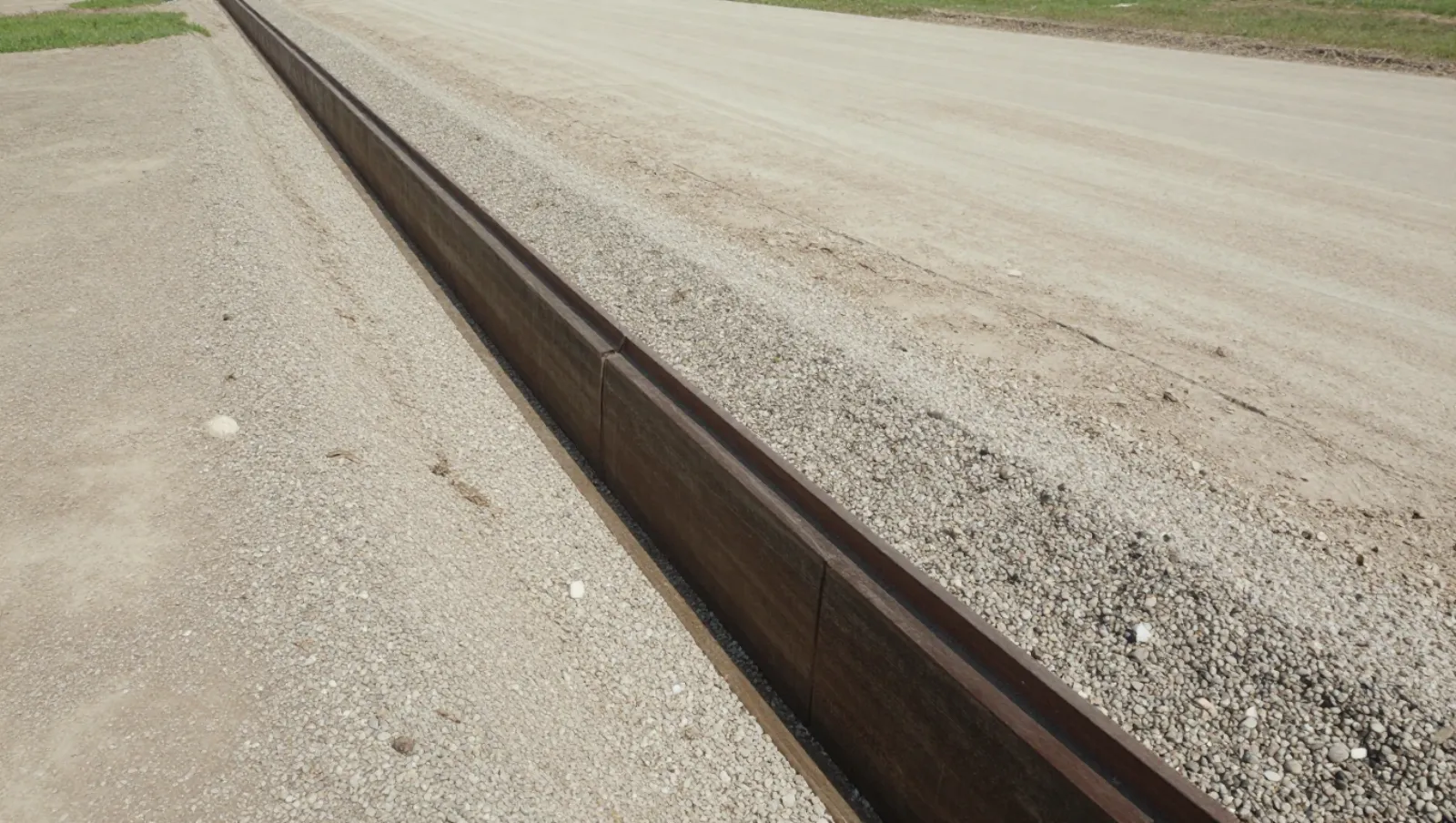 Concrete barriers installed on gravel terrain beside paved road for construction work — Daniel Dean Land Clearing, Southeast Texas