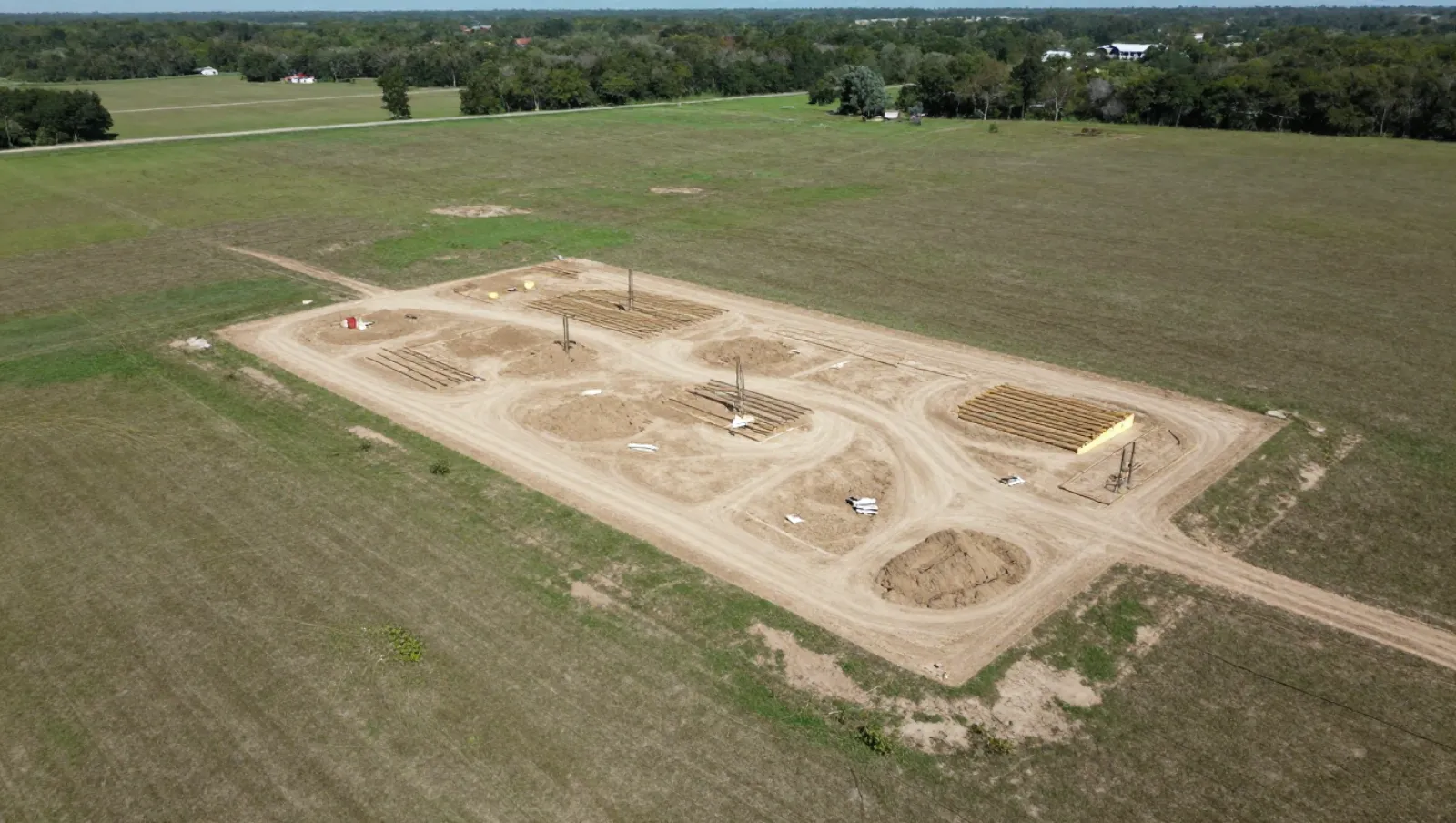 Grassy terrain has foundation pits with rebar for construction; no machinery visible — Daniel Dean Land Clearing, Southeast Texas