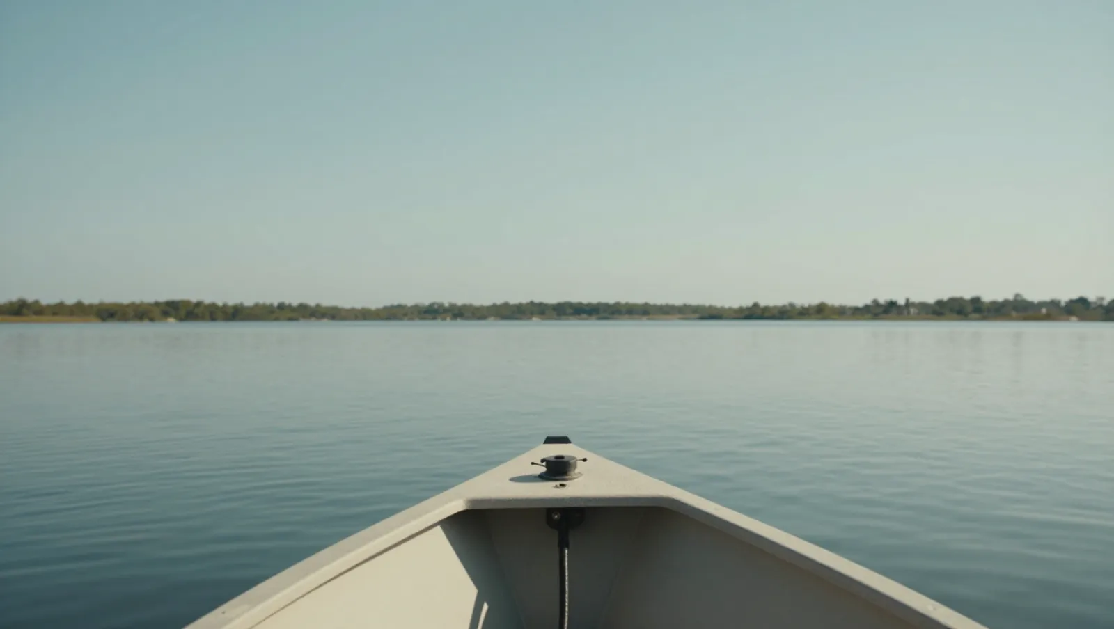 A canoe moves across calm waters toward forested shores under clear skies — Daniel Dean Land Clearing, Southeast Texas