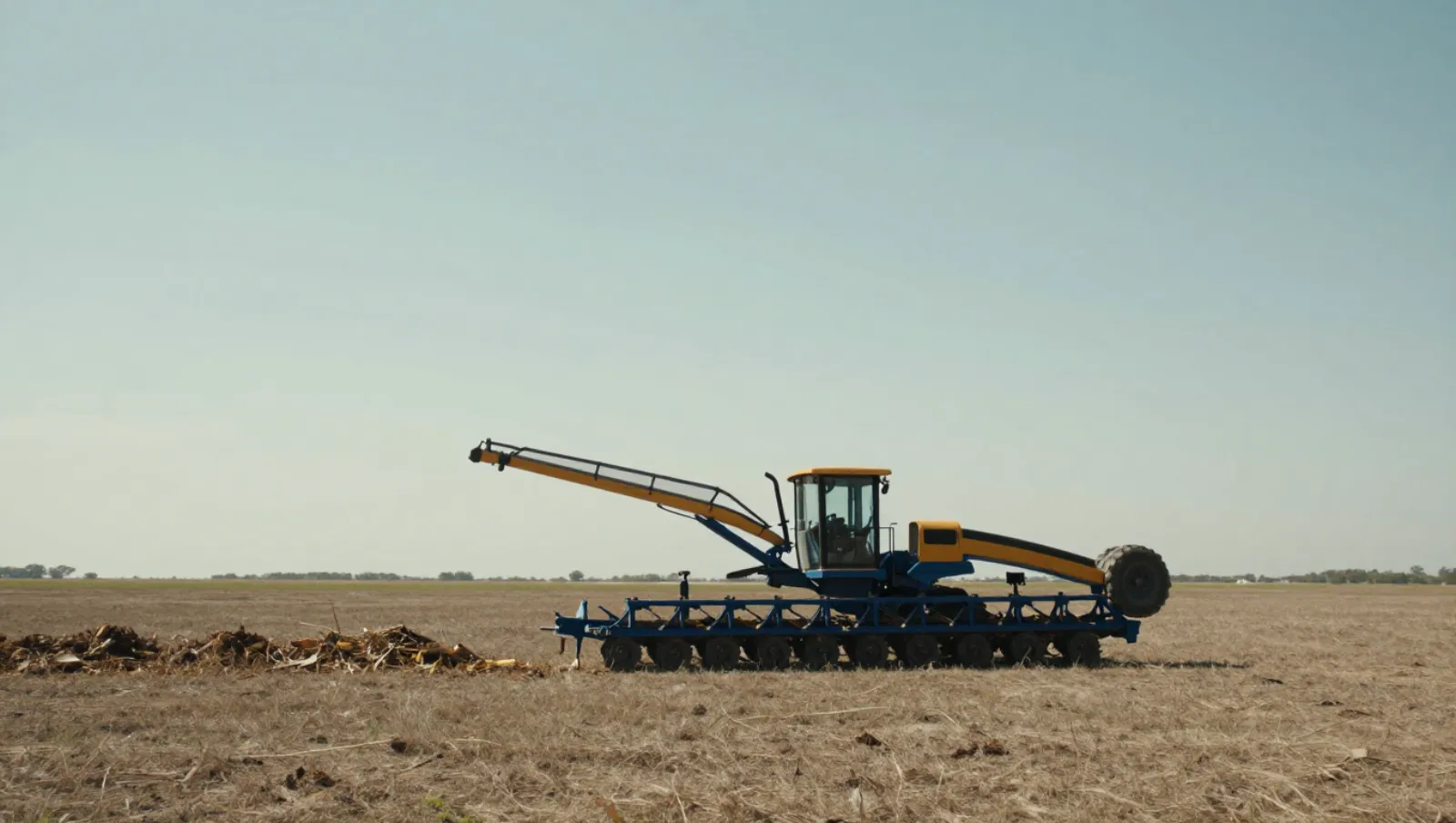 Blue-and-yellow combine harvester harvests crops in a dry open field — Daniel Dean Land Clearing, Southeast Texas