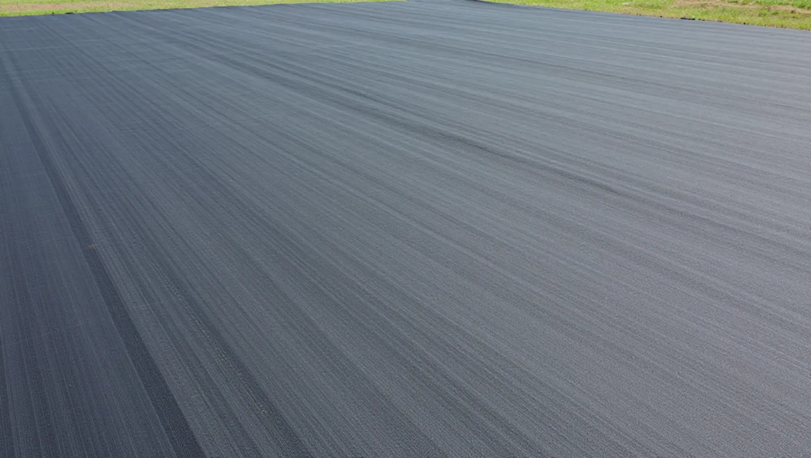 Types of Grass in Lawn for Texas Homes and Large Properties Grassy terrain covered by large dark tarp; no machinery visible, work involves ground covering — Daniel Dean Land Clearing, Southeast Texas