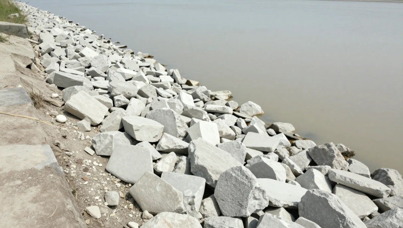 Yard Flooding: Why Water Stays After Every Rain | Daniel Dean Rocks line a riverbank embankment for erosion control; no machinery present — Daniel Dean Land Clearing, Southeast Texas