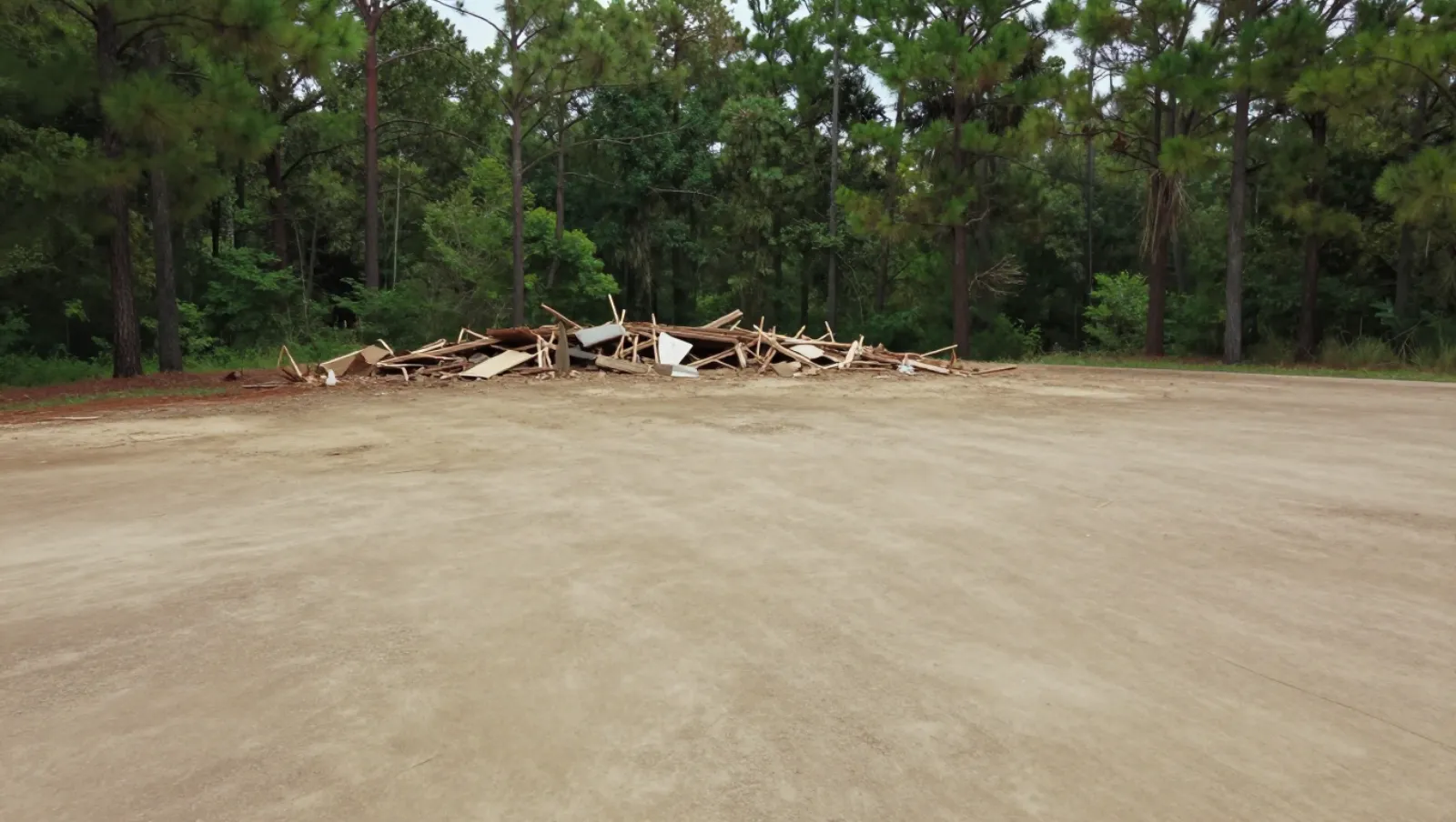 Demolition in Conroe, Texas — completed work Dirt field holds demolished wooden debris; no machinery present — demolition in Conroe, Texas