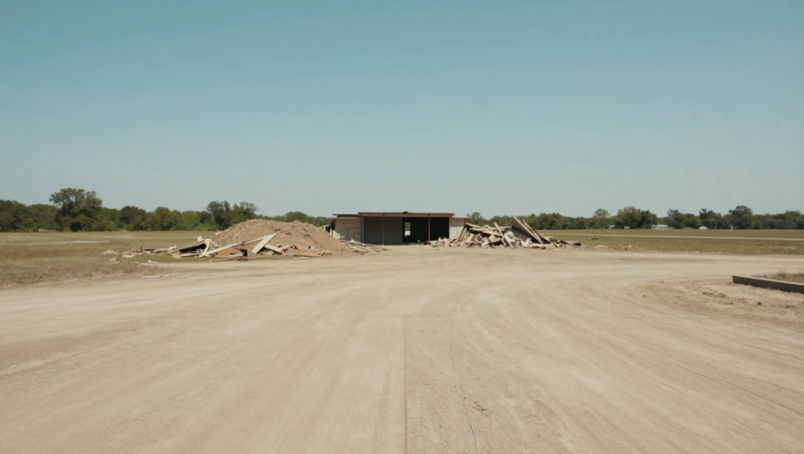 Demolition in Cypress, Texas — completed work Dirt terrain has debris piles near a small building; no machinery present during construction work — demolition in Cypress, Texas