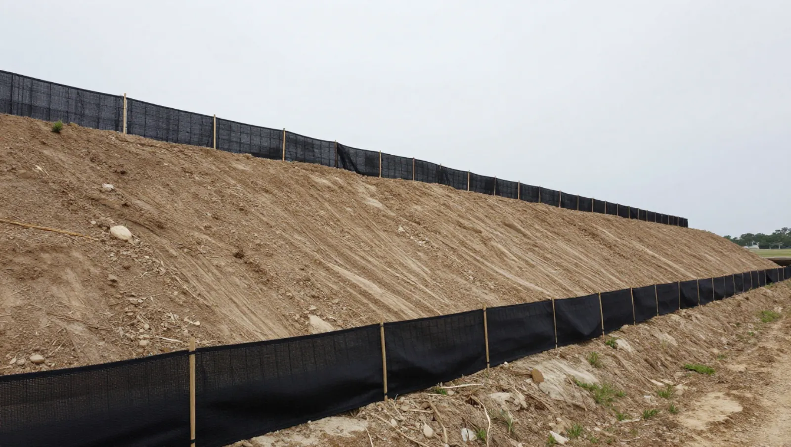 Erosion control in Katy, Texas — Daniel Dean Land Clearing Silt fences control erosion on a sloped dirt embankment; no machinery present — erosion control in Katy, Texas