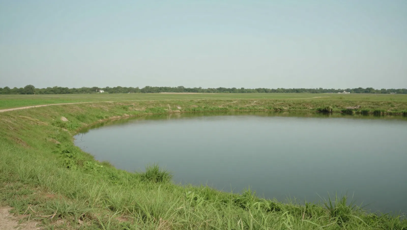 Pond services in Dayton, Texas — completed work No machinery visible; terrain is grassy fields bordering a calm pond with no work being done — pond dredging and construction in Dayton, Texas