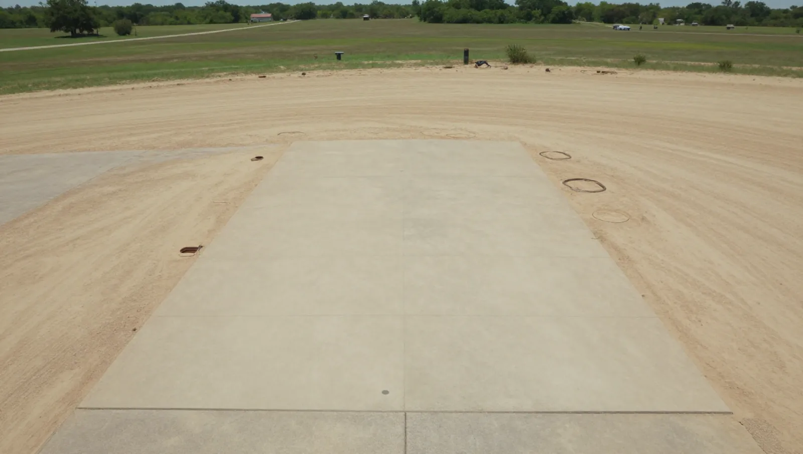 Excavation and site development in Atascocita, Texas — completed work Sandy terrain features a concrete slab with circular holes; drilling machinery prepared the site for foundation work — excavation and site development in Atascocita, Texas