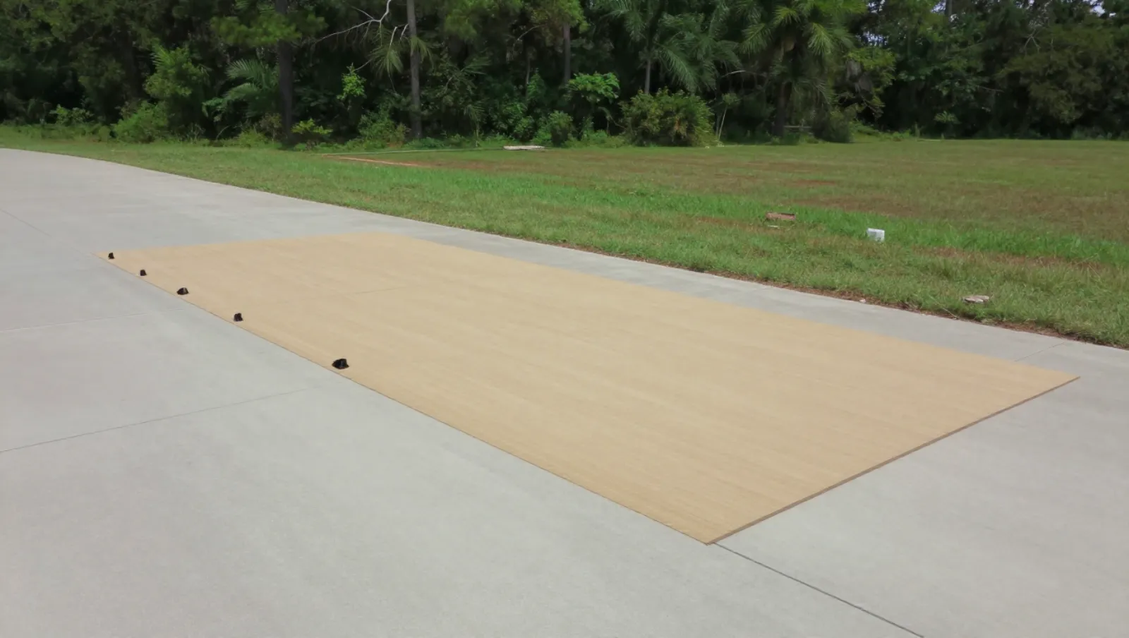 Excavation and site development in Conroe, Texas — completed work No visible machinery; terrain: concrete pavement next to grassy field with trees; black markers mark work placement on a beige platform — excavation and site development in Conroe, Texas