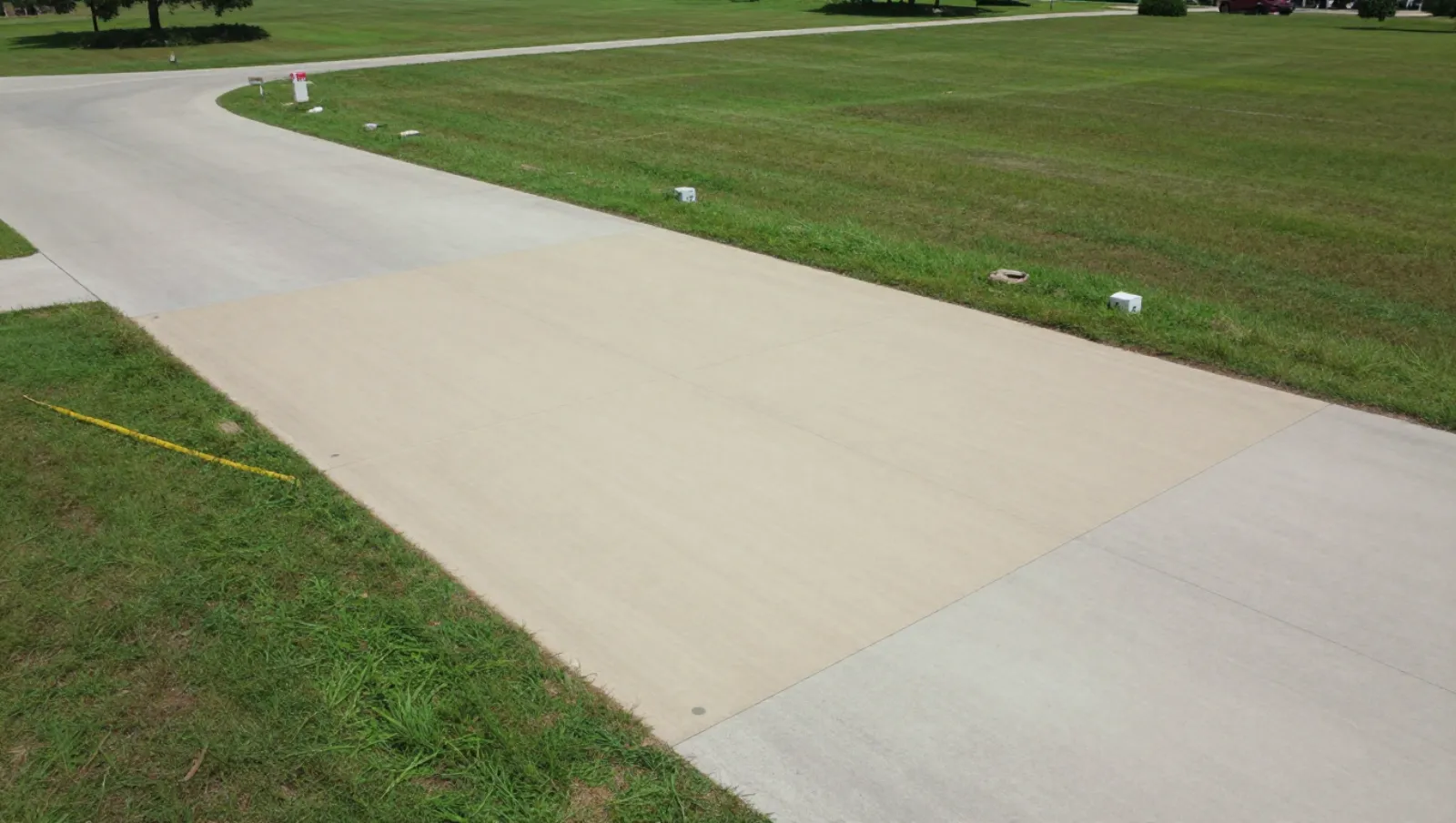 Excavation and site development in Tomball, Texas — completed work Concrete paver installs new driveway slabs on grassy terrain adjacent to paved paths — excavation and site development in Tomball, Texas