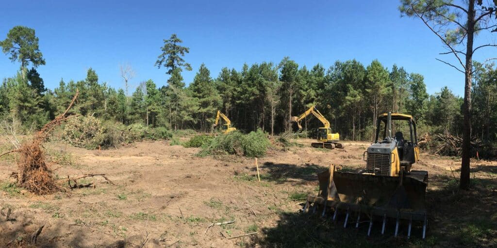 Cleared Texas acreage with stacked brush and standing timber at the tree line - Daniel Dean Land Clearing, Southeast Texas